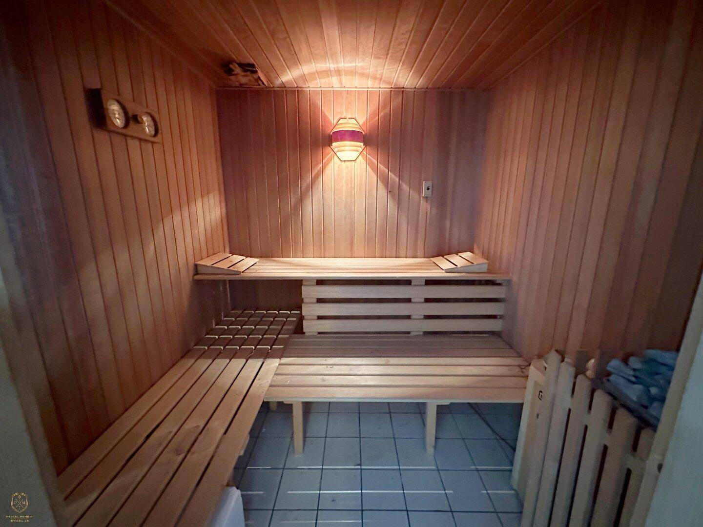 Gemütliche Holzsauna mit Sitzbänken und stimmungsvoller Beleuchtung.