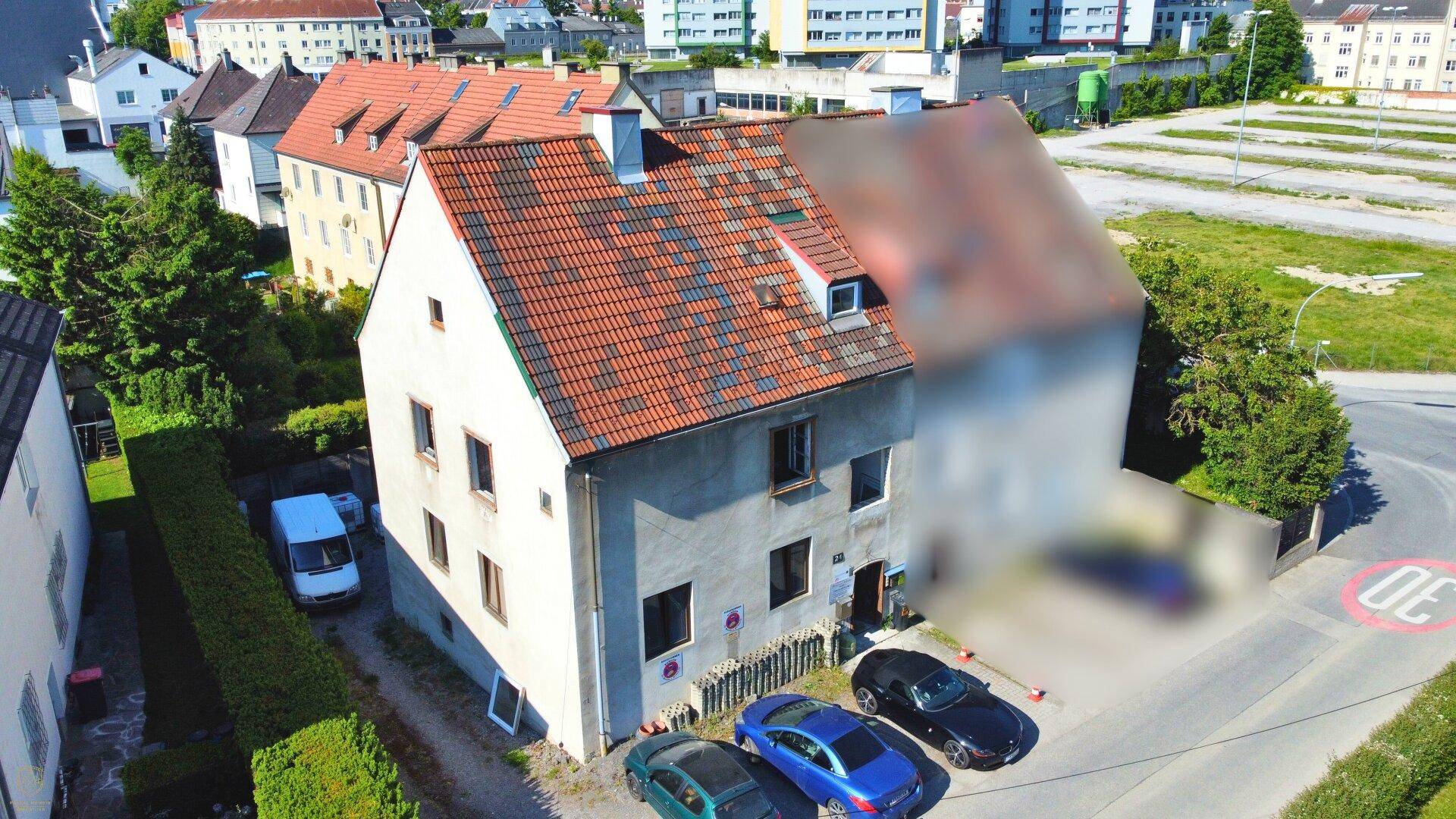 Luftaufnahme eines Wohnhauses mit Ziegeldach, umgeben von weiteren Gebäuden und einer Straße.