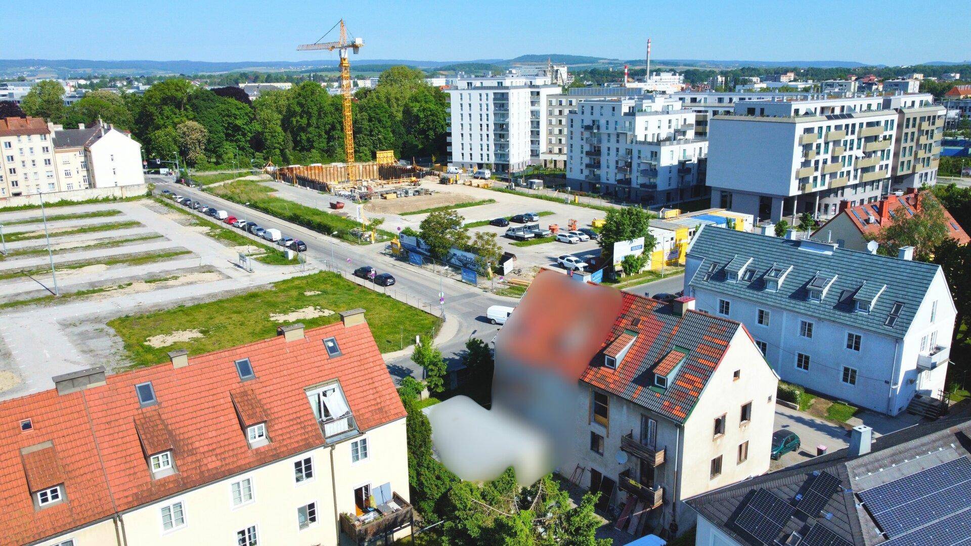 Weitläufige Luftaufnahme einer städtischen Umgebung mit Wohngebäuden und Baustellen im Hintergrund.