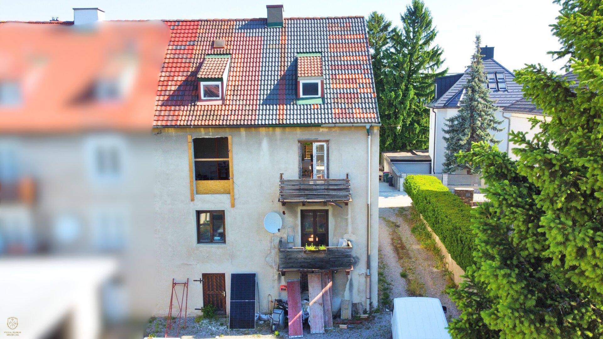 Nahaufnahme der Gebäudefassade mit Ziegeldach, Gaubenfenstern und einem kleinen Balkon.