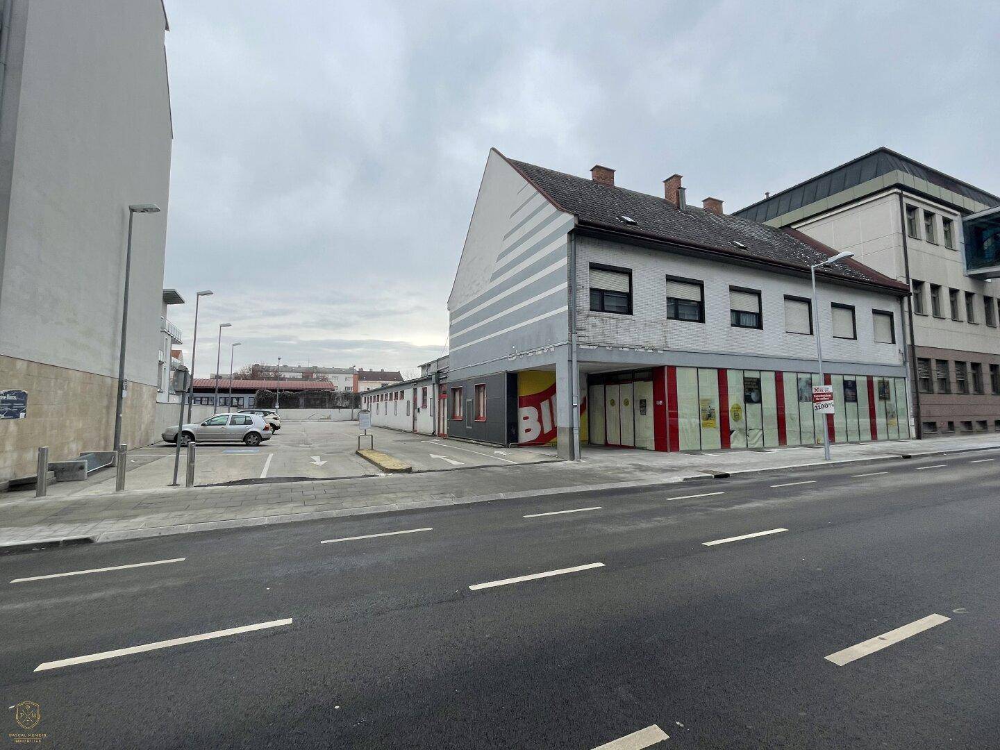 Seitenansicht des Gebäudes mit angrenzendem Parkplatz und Blick auf die umliegende Bebauung.