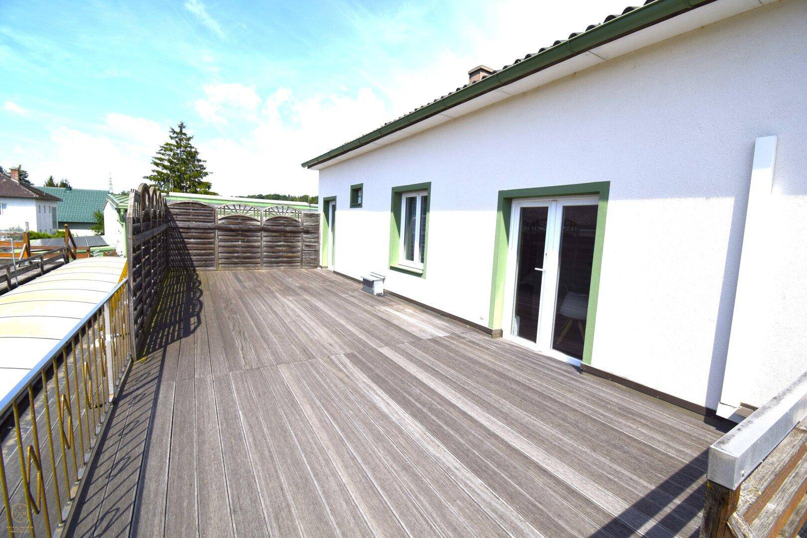 Große Holzterrasse auf dem Dach mit Blick ins Grüne und umliegende Häuser.