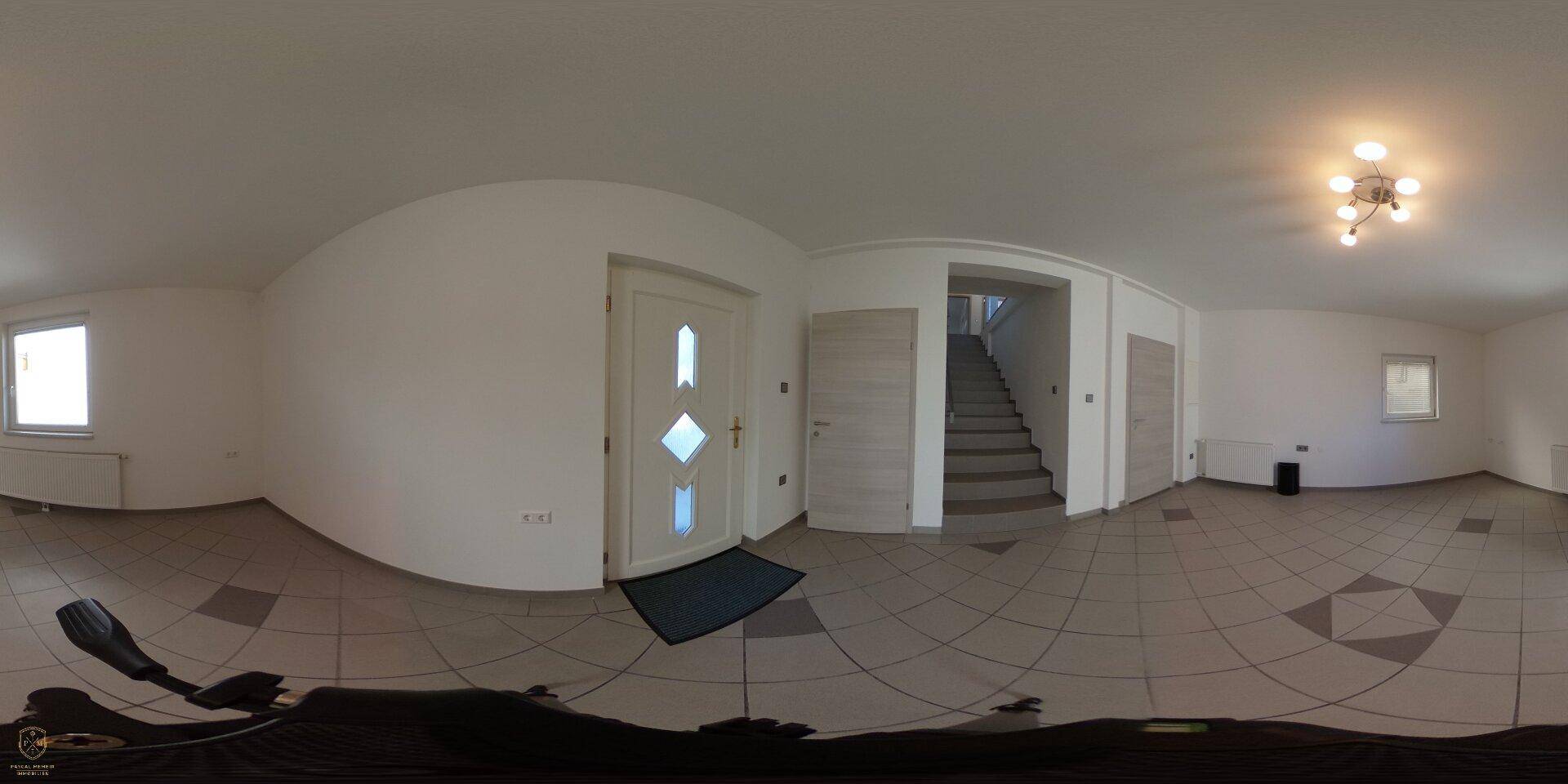Panoramaaufnahme eines geräumigen Eingangsbereichs mit Fliesenboden und Treppenaufgang.