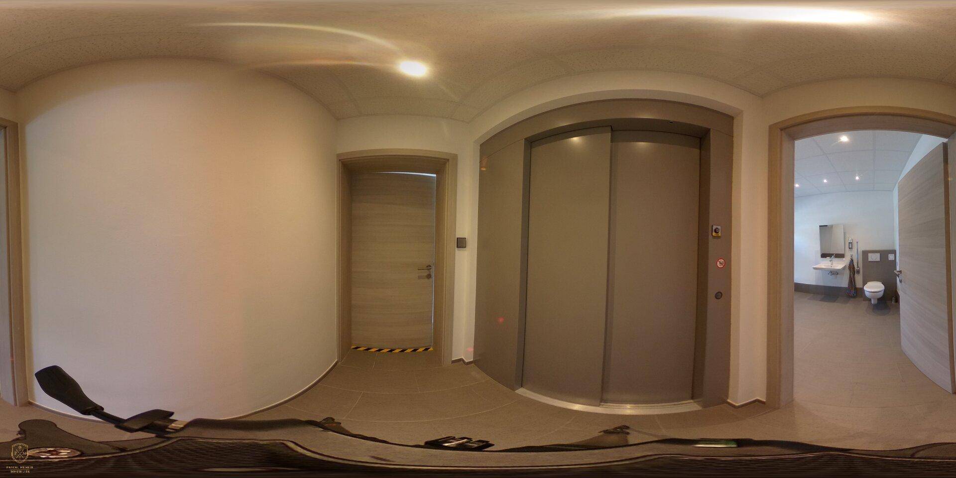 Panoramaaufnahme eines Flurs mit Aufzug und Zugang zu weiteren Räumen.