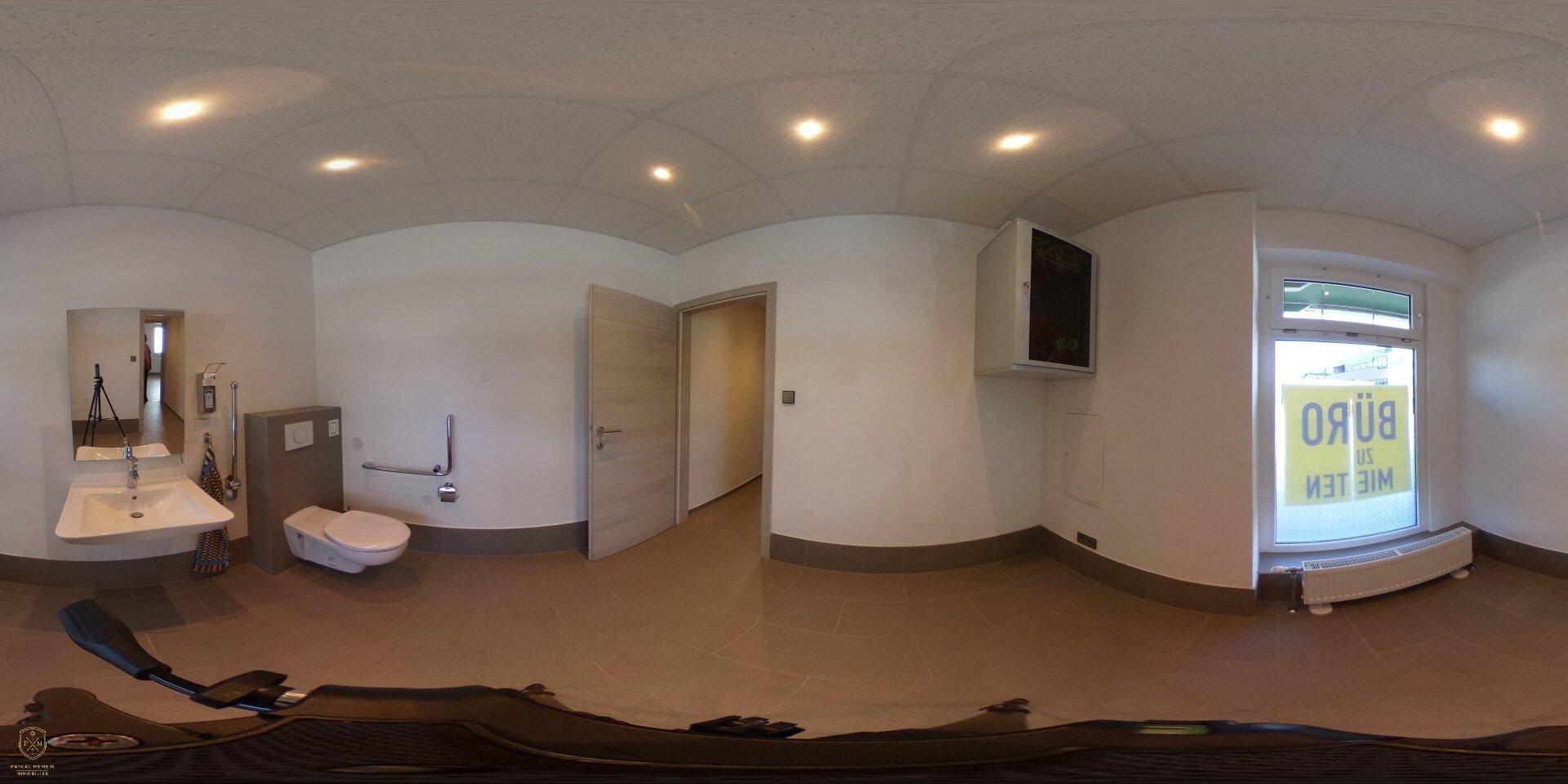 Panoramaaufnahme eines Badezimmers mit Waschbecken, WC und Fenster, das viel Licht hereinlässt.