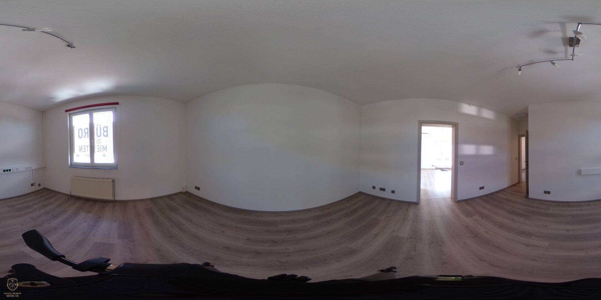 Panoramaaufnahme eines leeren Büroraums mit Laminatboden und großem Fenster.