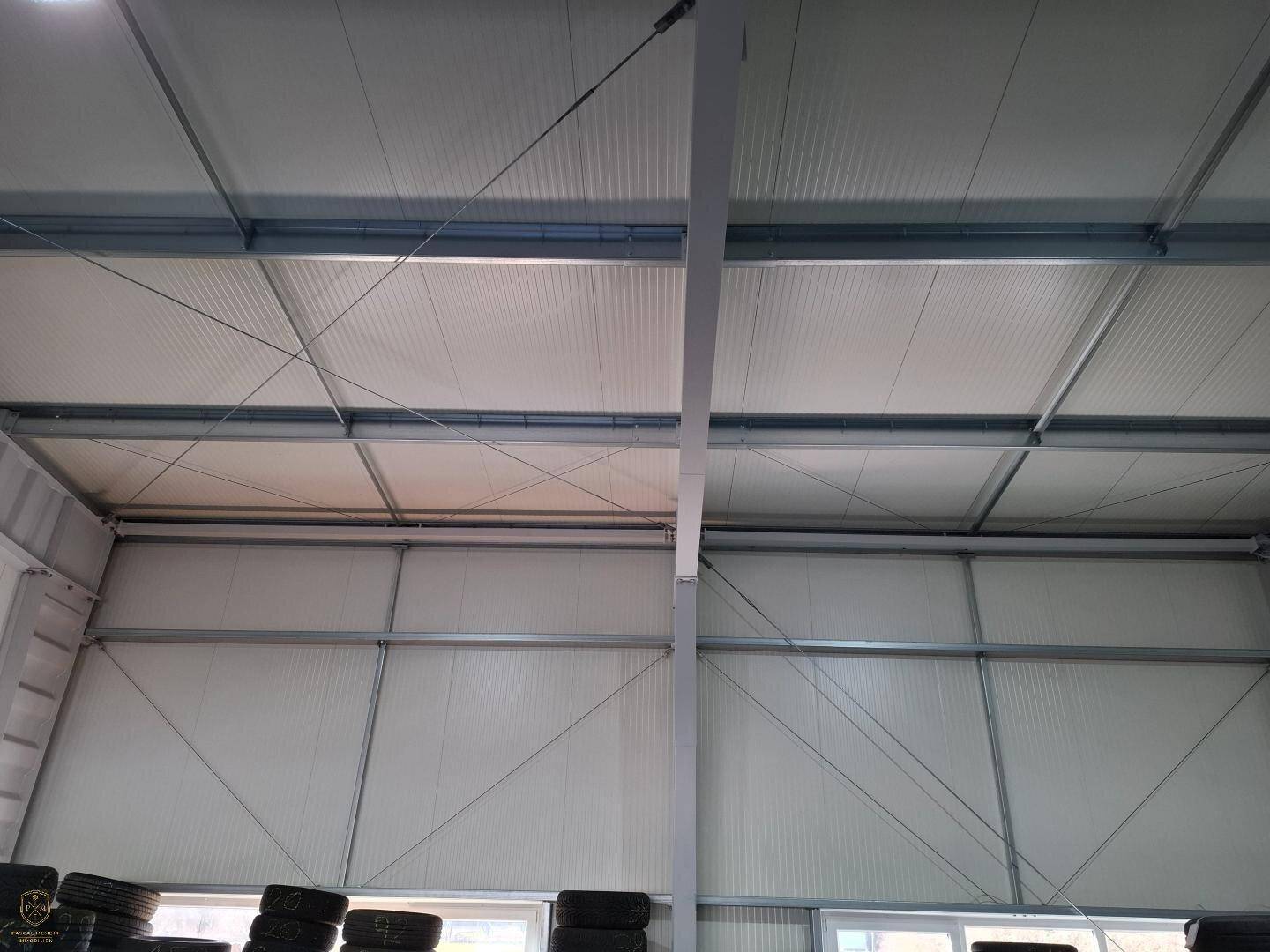 Blick auf die hohe Deckenkonstruktion und die Wände einer modernen Industriehalle.