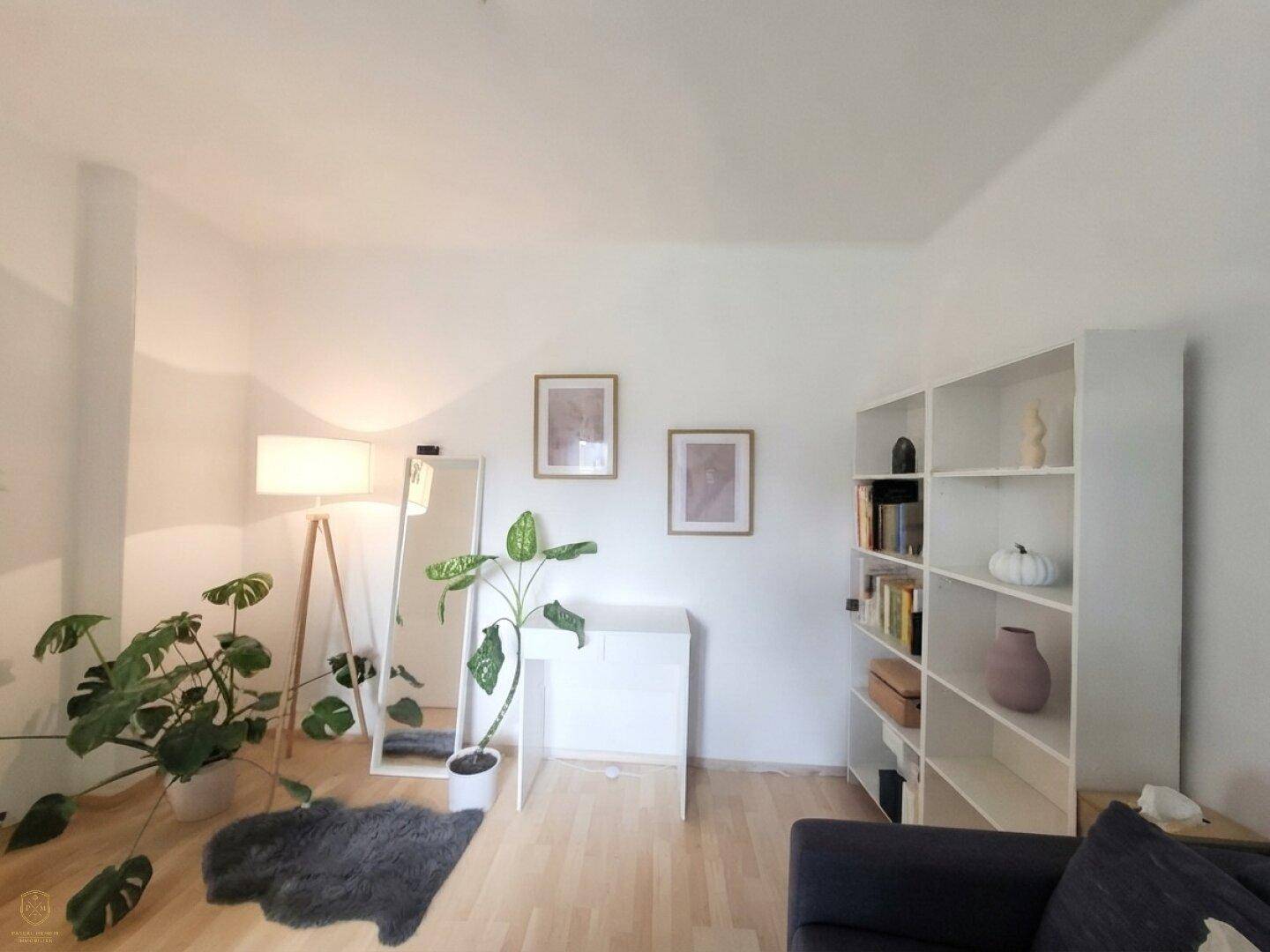 Heller Wohnbereich mit Bücherregal, Stehlampe und Pflanzen, der eine offene Atmosphäre schafft.
