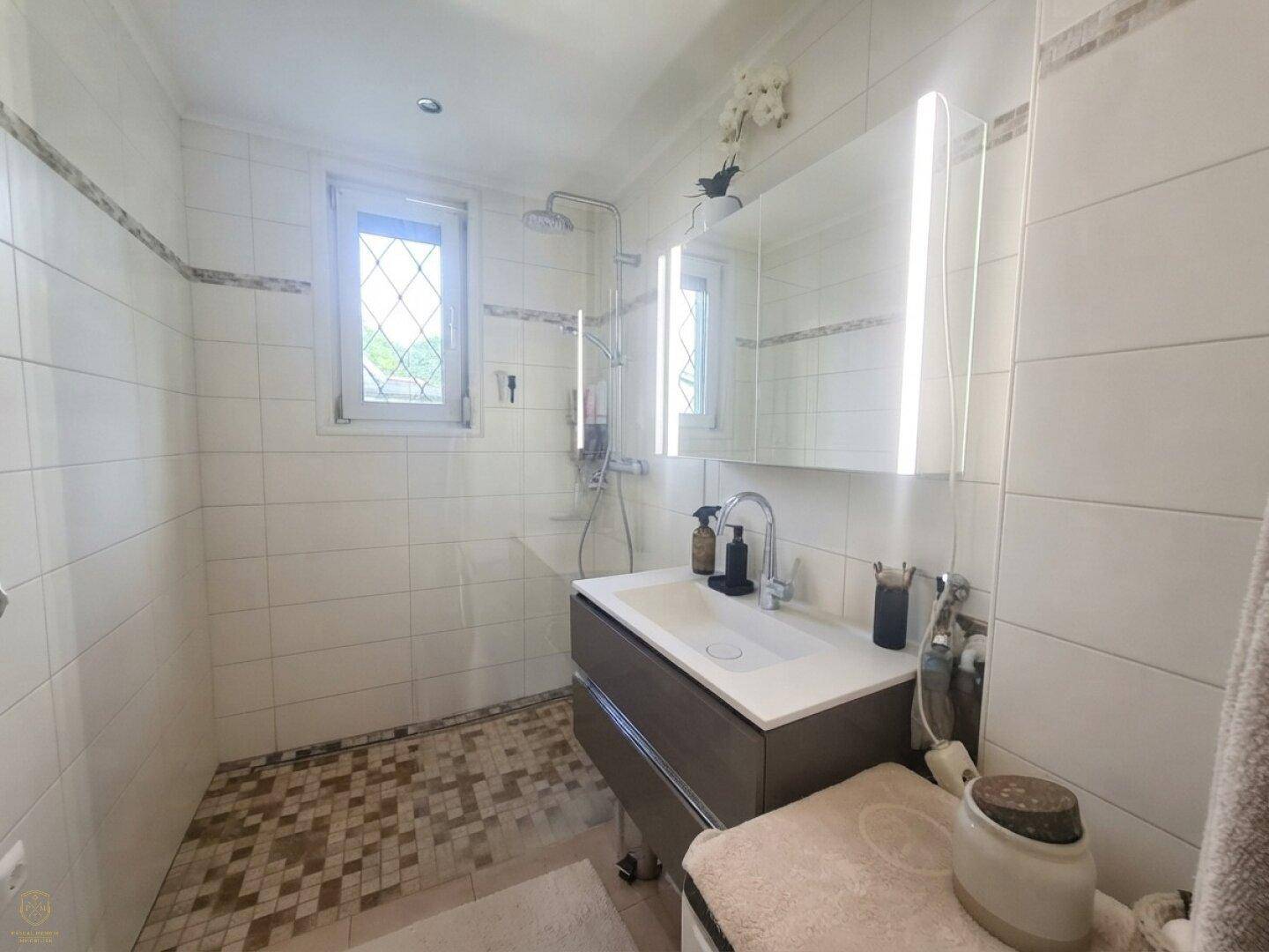 Modernes Badezimmer mit begehbarer Dusche, Waschtisch und Fenster für natürliche Belüftung.