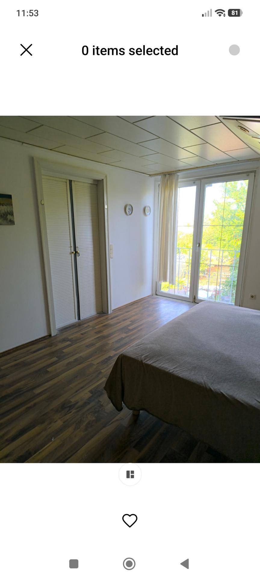 Schlafzimmer mit großem Fenster, das viel Tageslicht hereinlässt und einen Blick ins Grüne bietet.