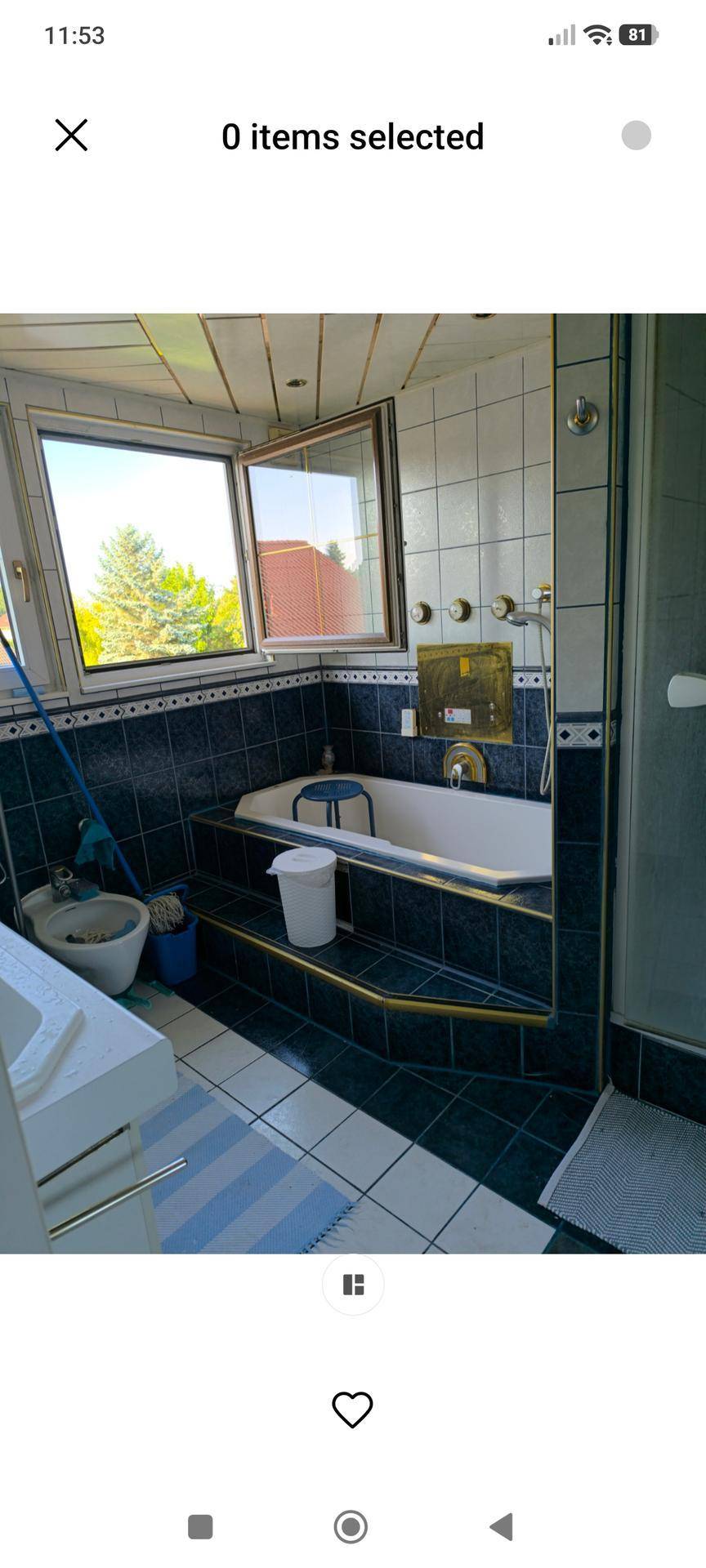 Badezimmer mit eingebauter Badewanne, Dusche und Fenster, ausgestattet mit blauen und weißen Fliesen.