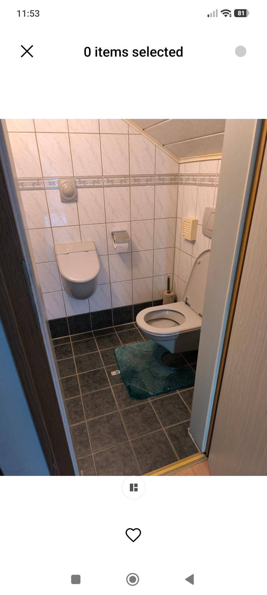 Kleines WC mit zwei Toiletten und dunklen Bodenfliesen, praktisch und funktional gestaltet.