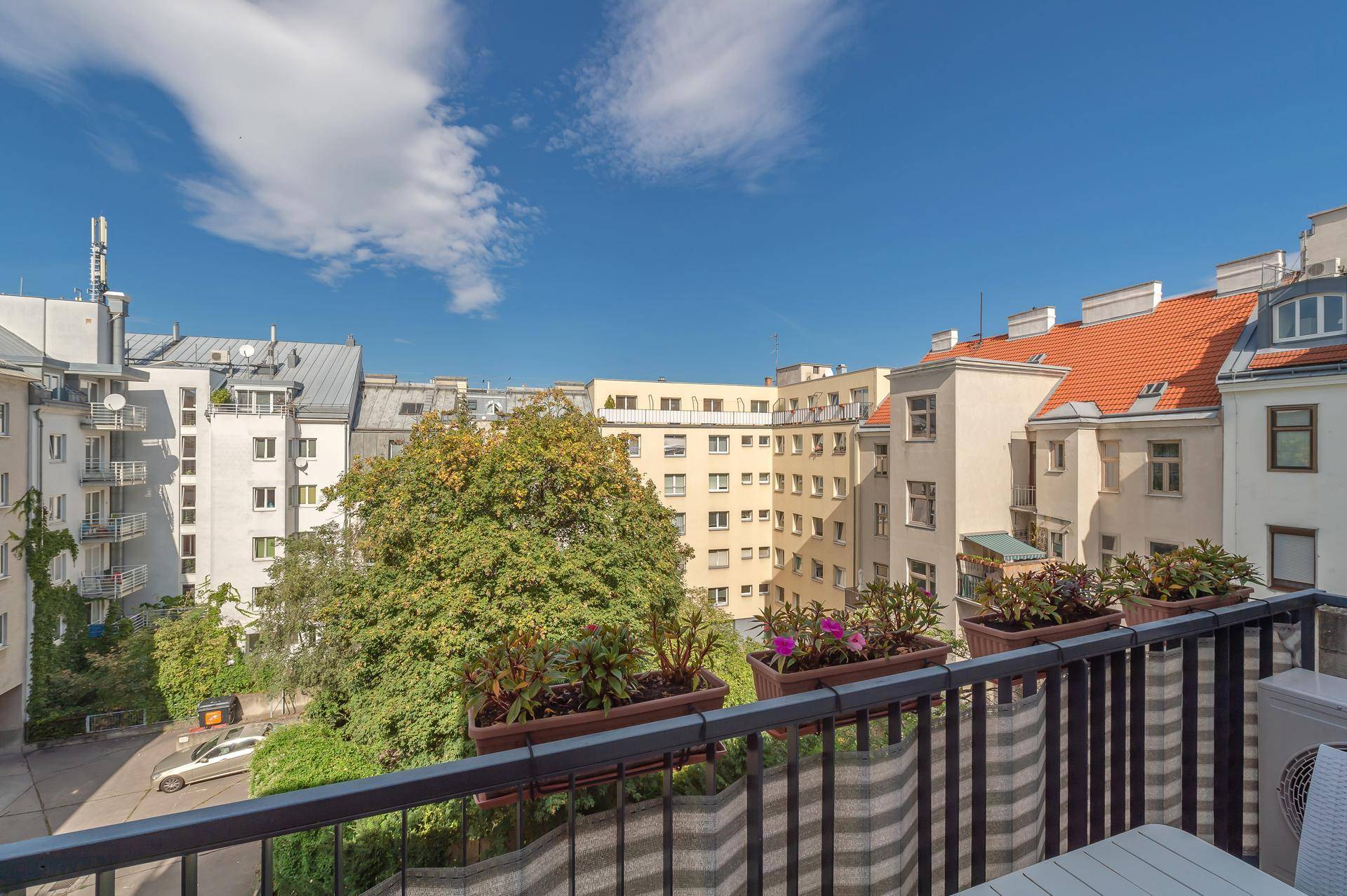 Balkon mit Blumenkästen und weitem Blick über die Dächer der Stadt.