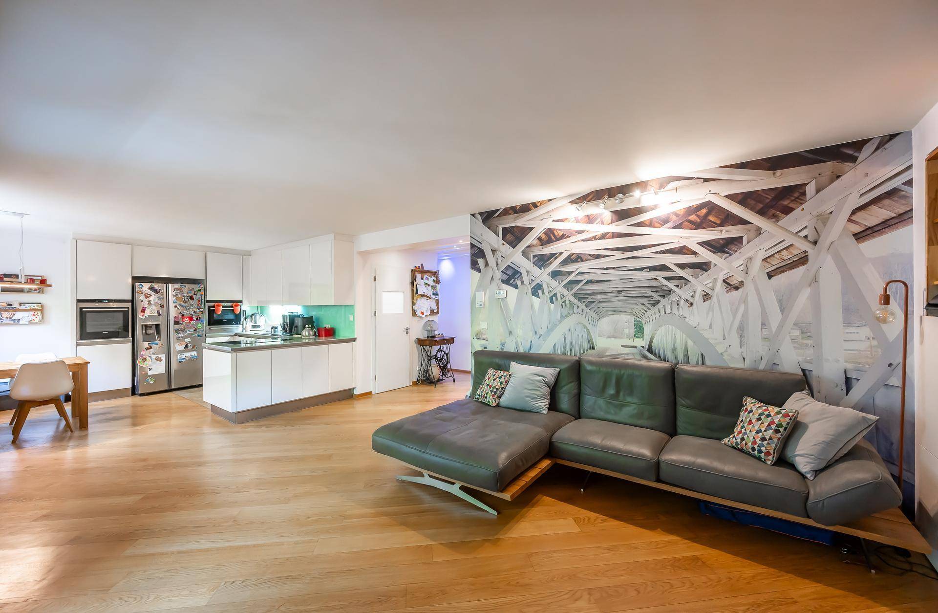 Großzügiger offener Wohn-Essbereich mit moderner Küche, Sofa und Holzboden.