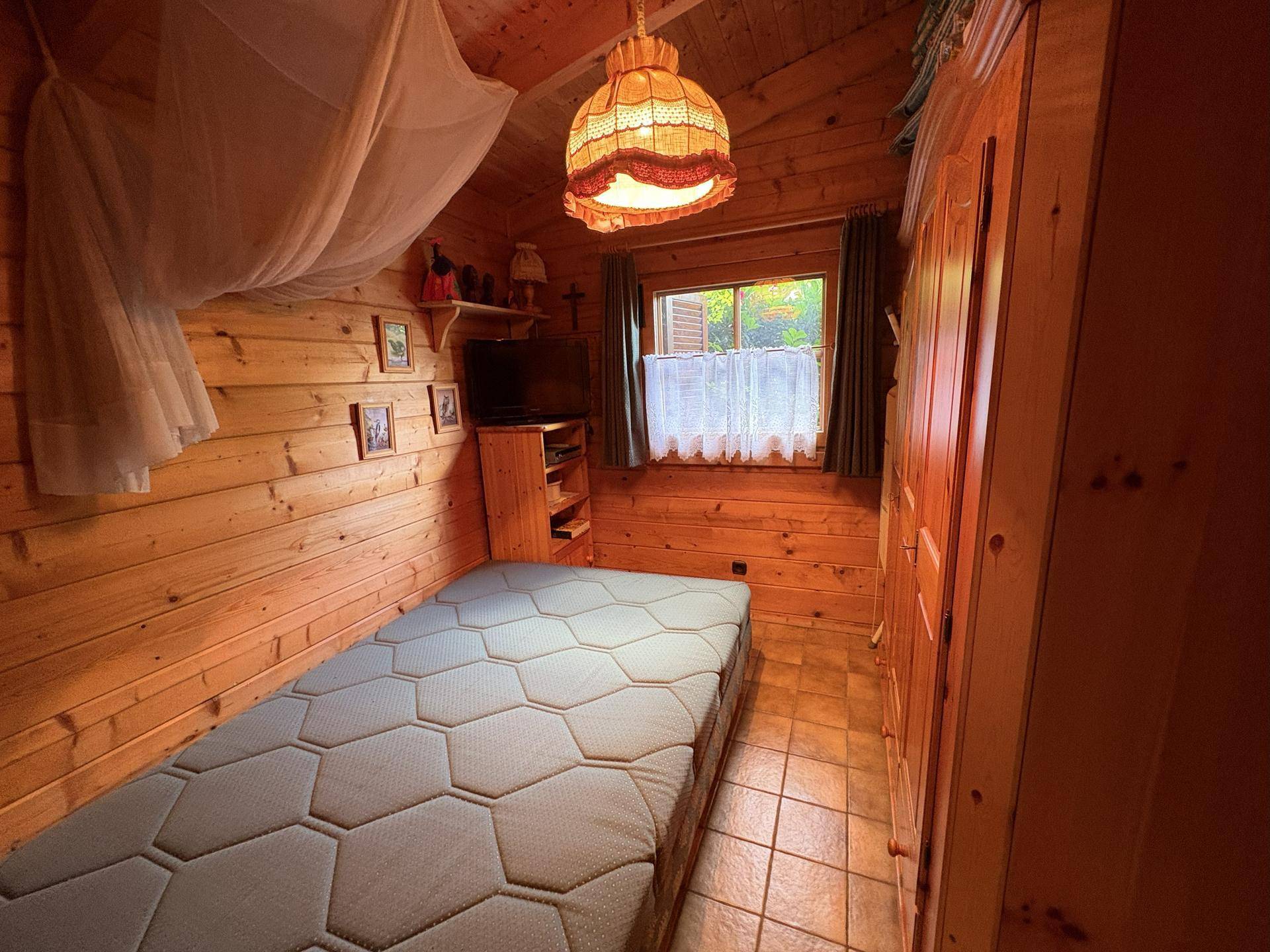 Gemütliches Schlafzimmer mit Holzwänden, Einzelbett und Kleiderschrank im rustikalen Stil.
