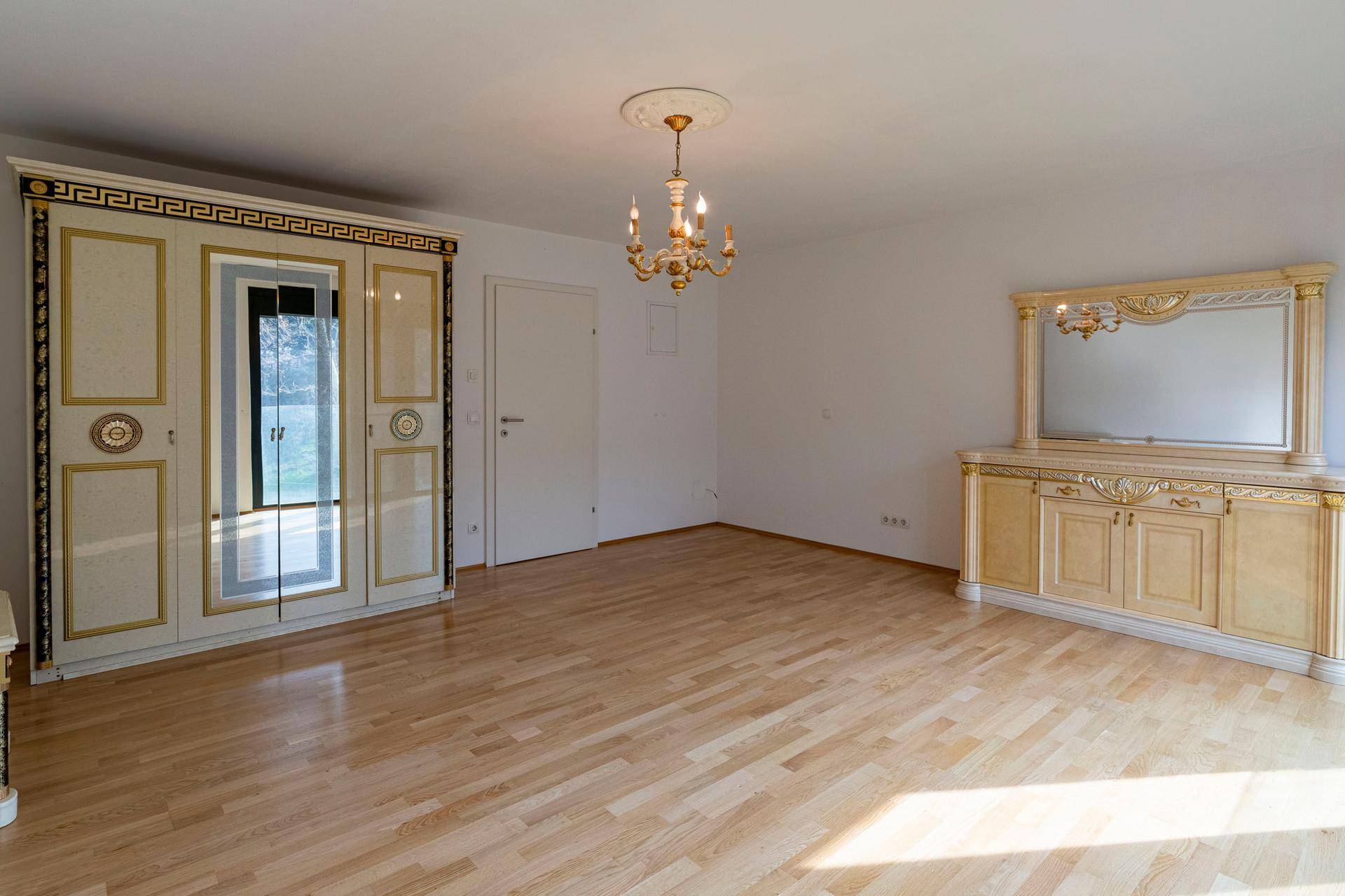 Geräumiges Schlafzimmer mit Parkettboden, klassischem Kleiderschrank und Kommode.