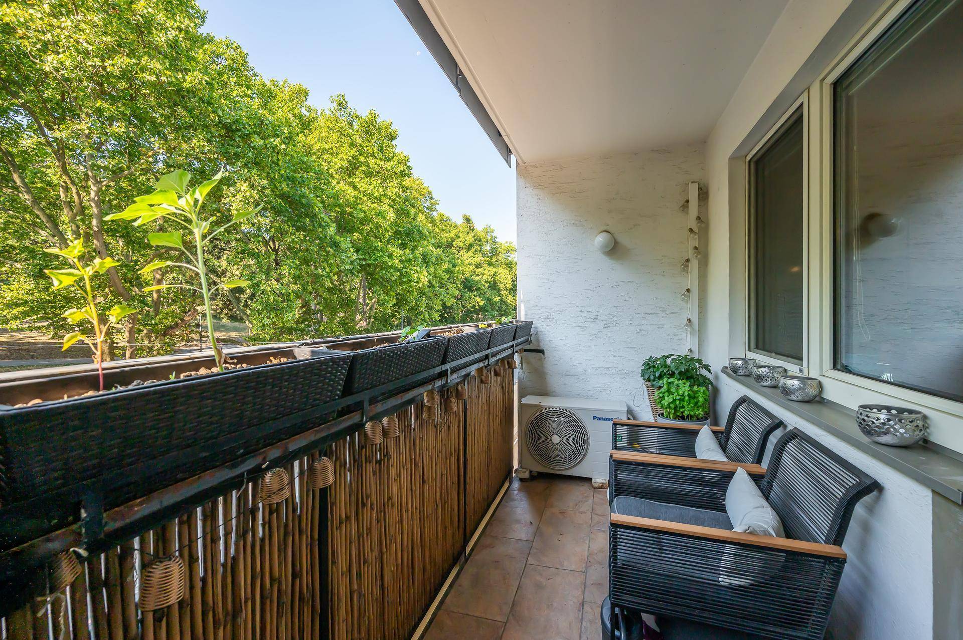 Gemütlicher Balkon mit Sitzgelegenheiten, Pflanzen und Blick ins Grüne.