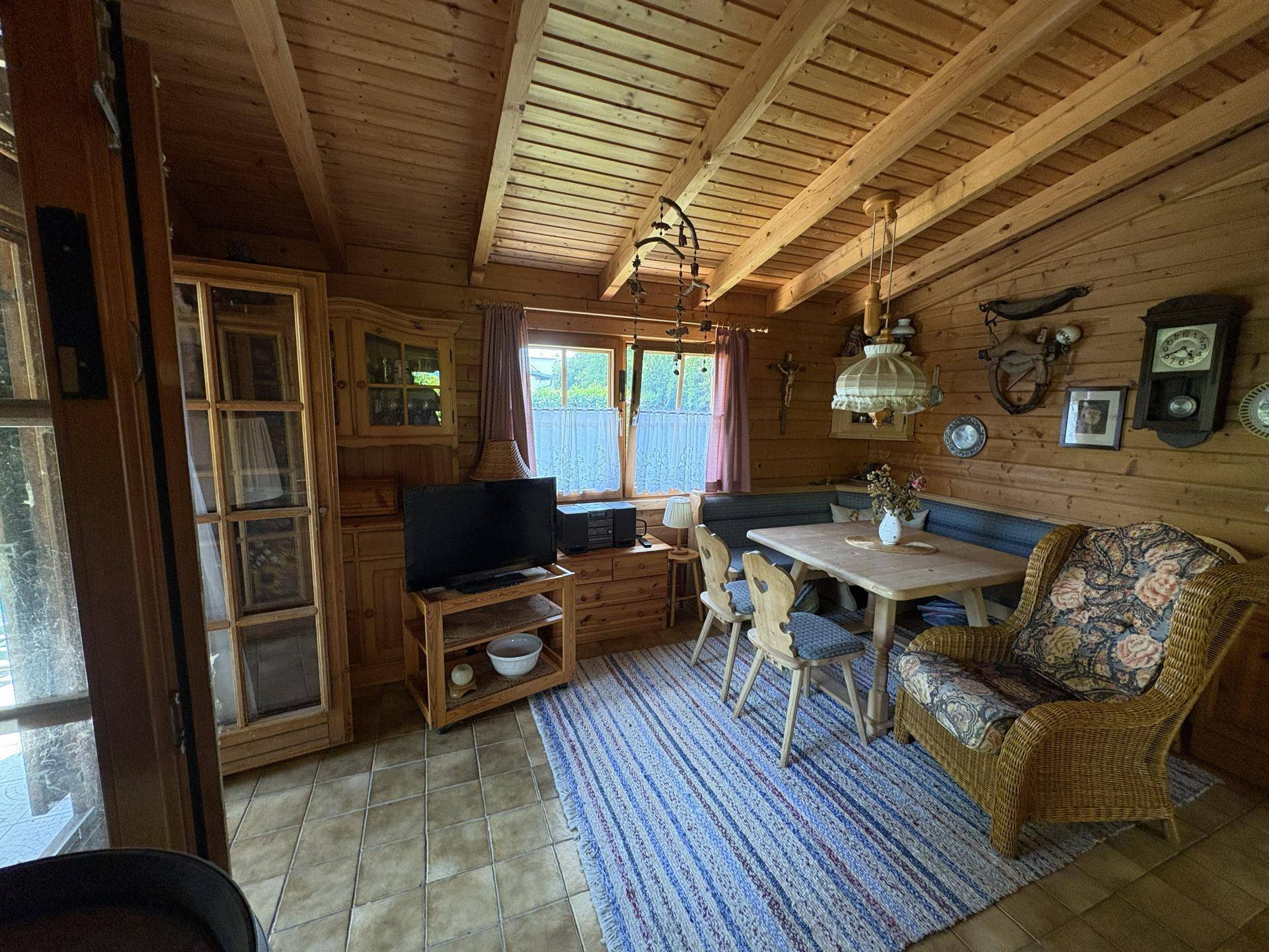 Rustikaler Wohn- und Essbereich mit Holzwänden, Holzbalkendecke und traditionellen Möbeln.