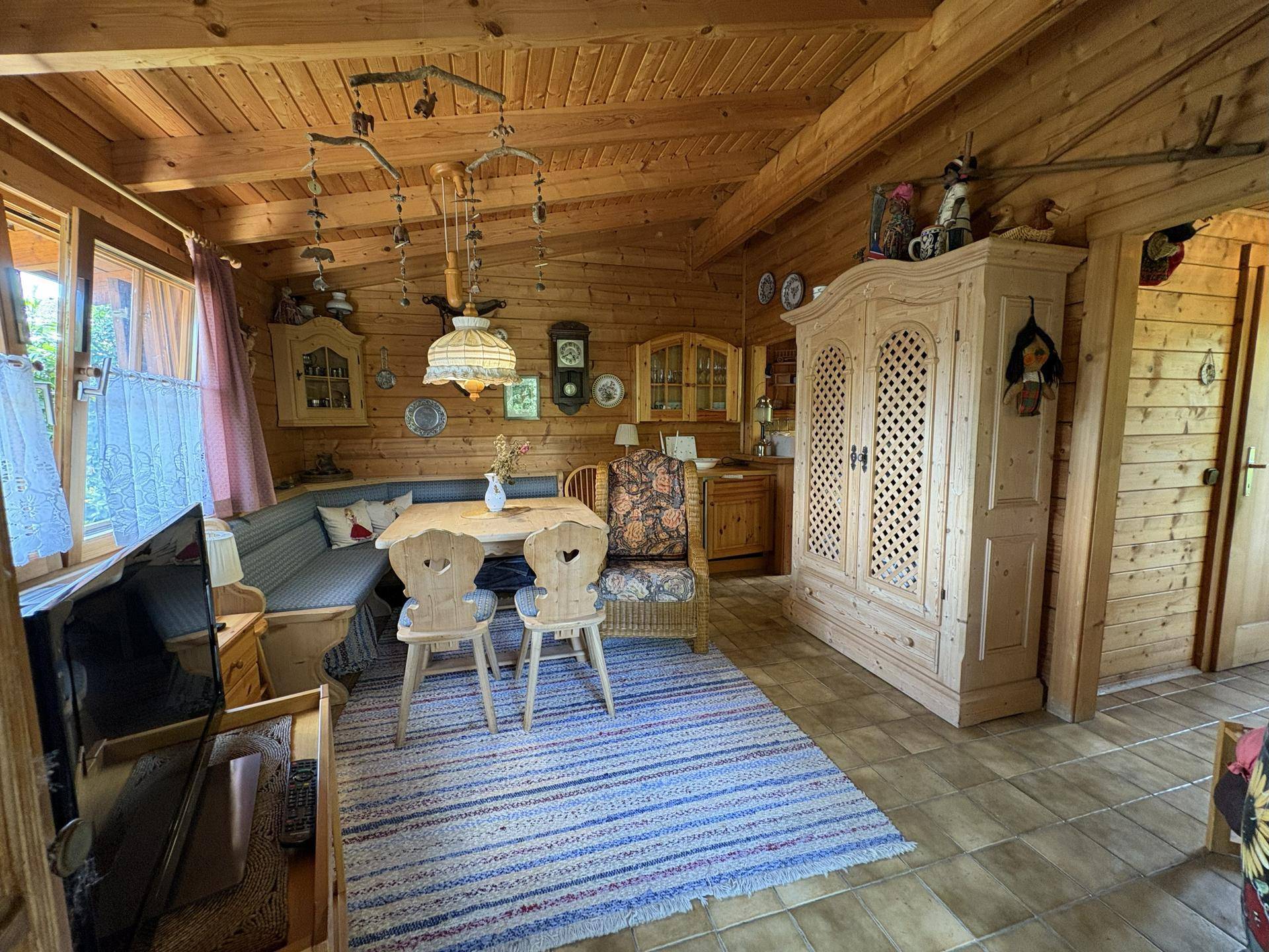 Gemütlicher Wohn- und Essbereich im Blockhausstil mit Holzwänden, Eckbank und rustikalem Schrank.