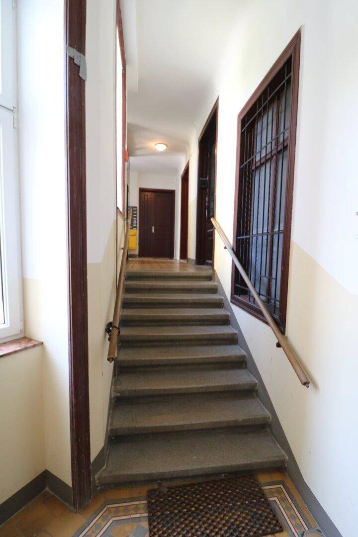 Historisches Treppenhaus mit Steinstufen und Holzgeländer in einem Altbau.