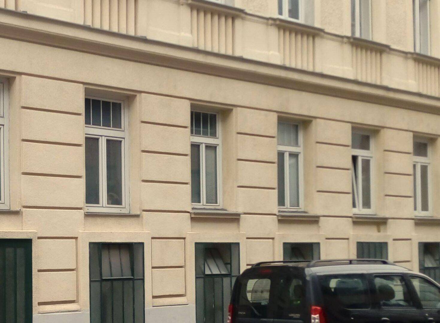 Fassade eines Altbaus mit klassischen Fenstern und dezenter Struktur.