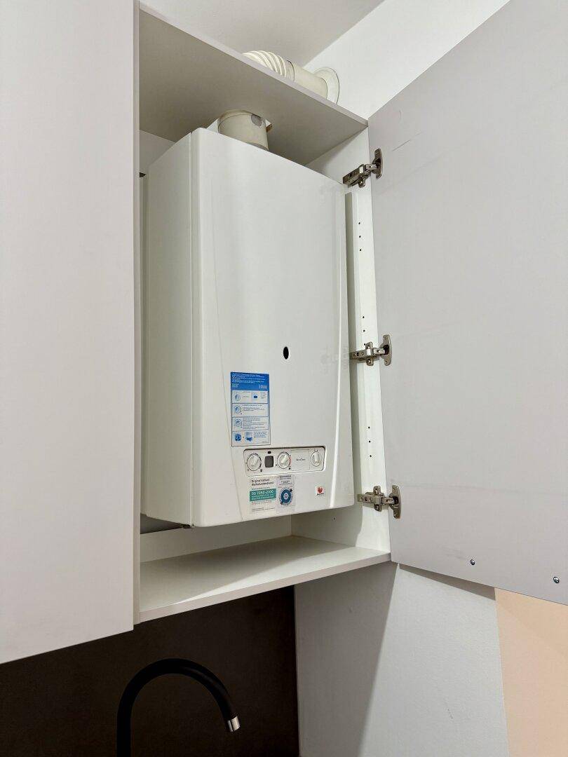 Wartungsbereich mit einem in einem Schrank verborgenen Warmwasserbereiter.