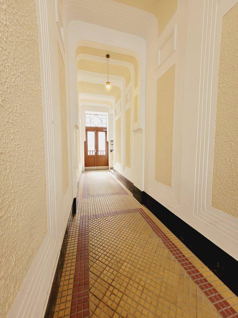 Langer, eleganter Flur mit kunstvoller Decke und gemustertem Fliesenboden, führt zum Eingangsbereich.