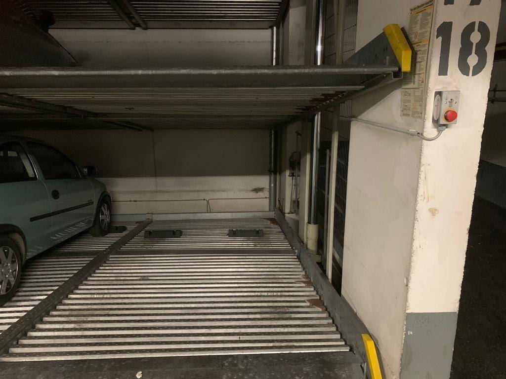 Detailansicht eines mechanischen Parksystems in der Tiefgarage mit einem geparkten Fahrzeug.