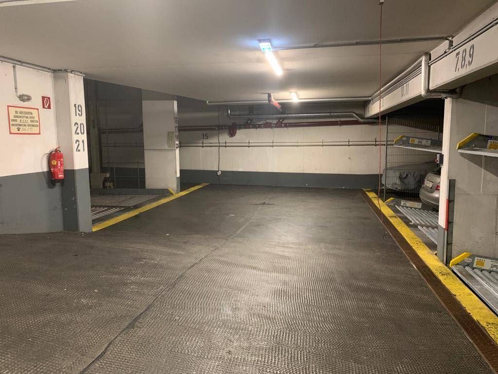 Geräumige Tiefgarage mit nummerierten Stellplätzen und mechanischen Parksystemen.