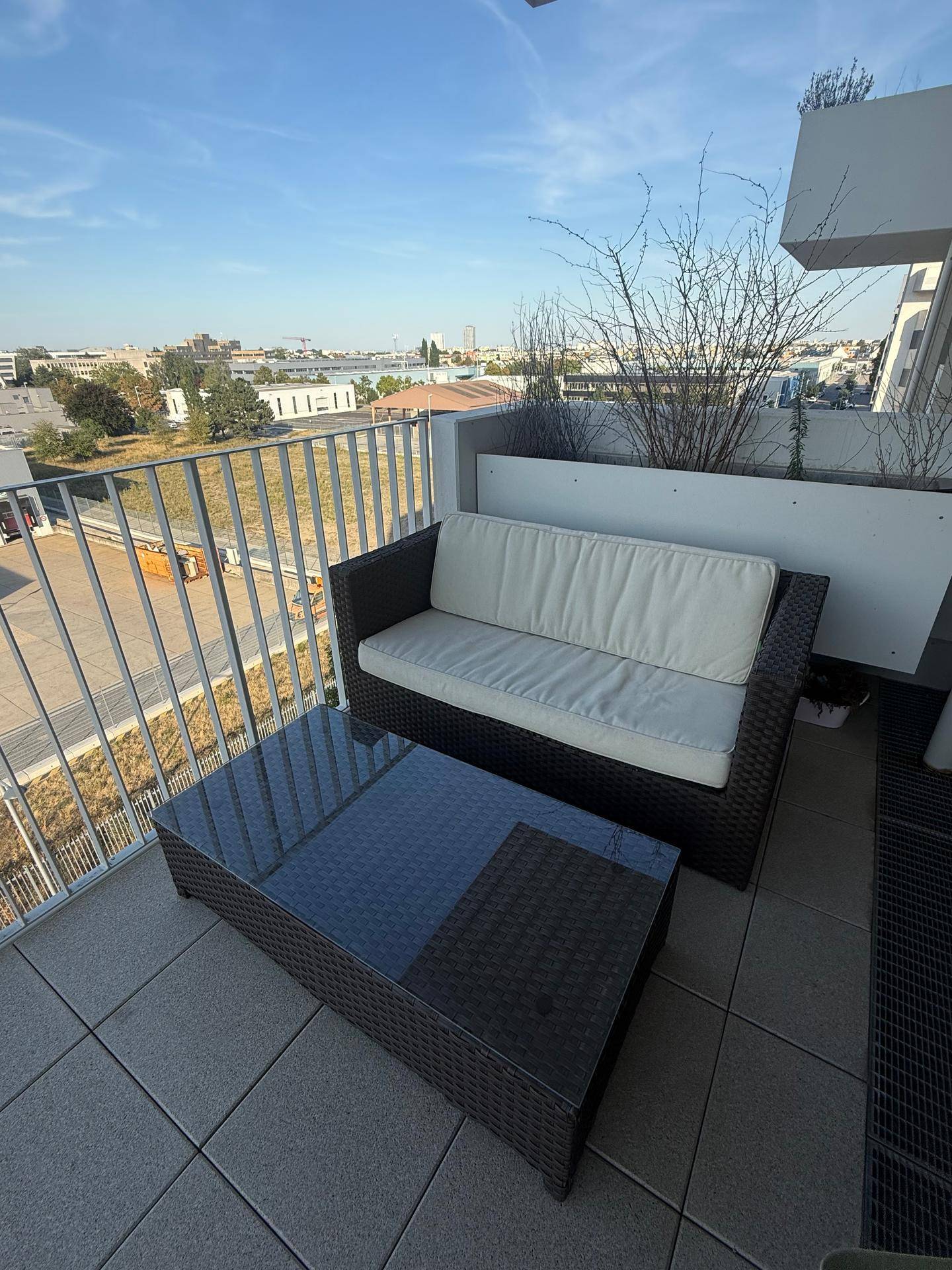 Geräumiger Balkon mit Fliesenboden, Outdoor-Sitzmöbeln und einem weiten Blick über die Stadt.