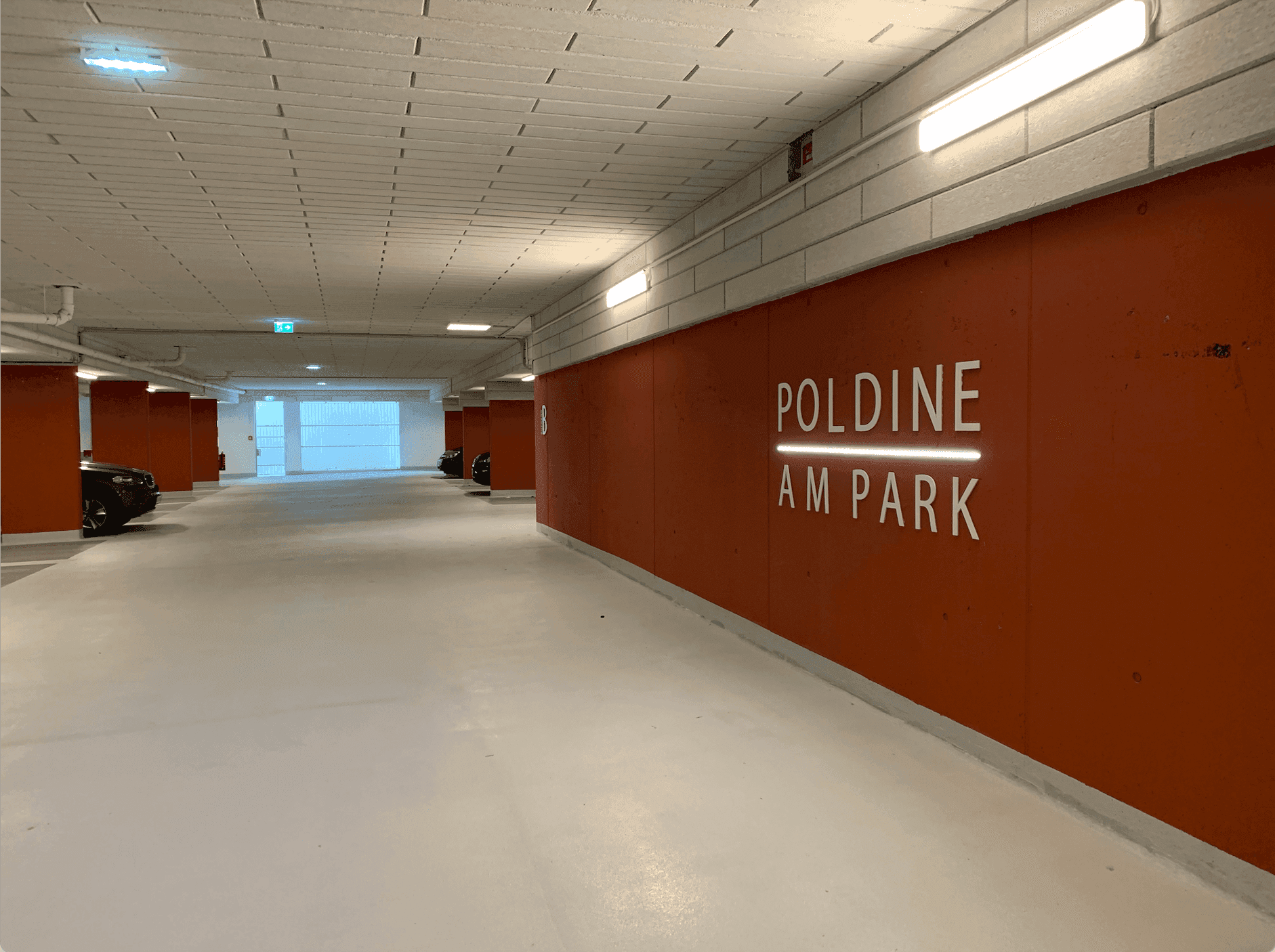 Moderne Tiefgarage mit breiten Fahrspuren und klarer Beschilderung.