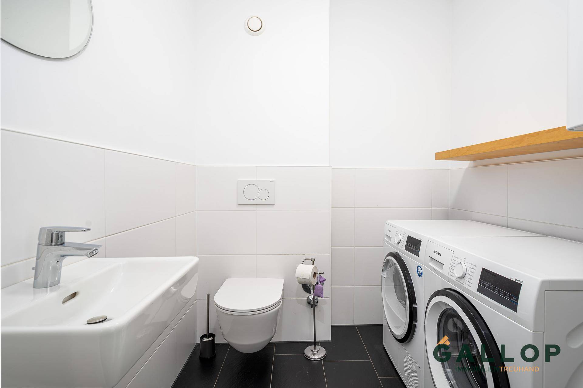 Praktischer Hauswirtschaftsraum mit WC, Waschbecken und Waschmaschine.