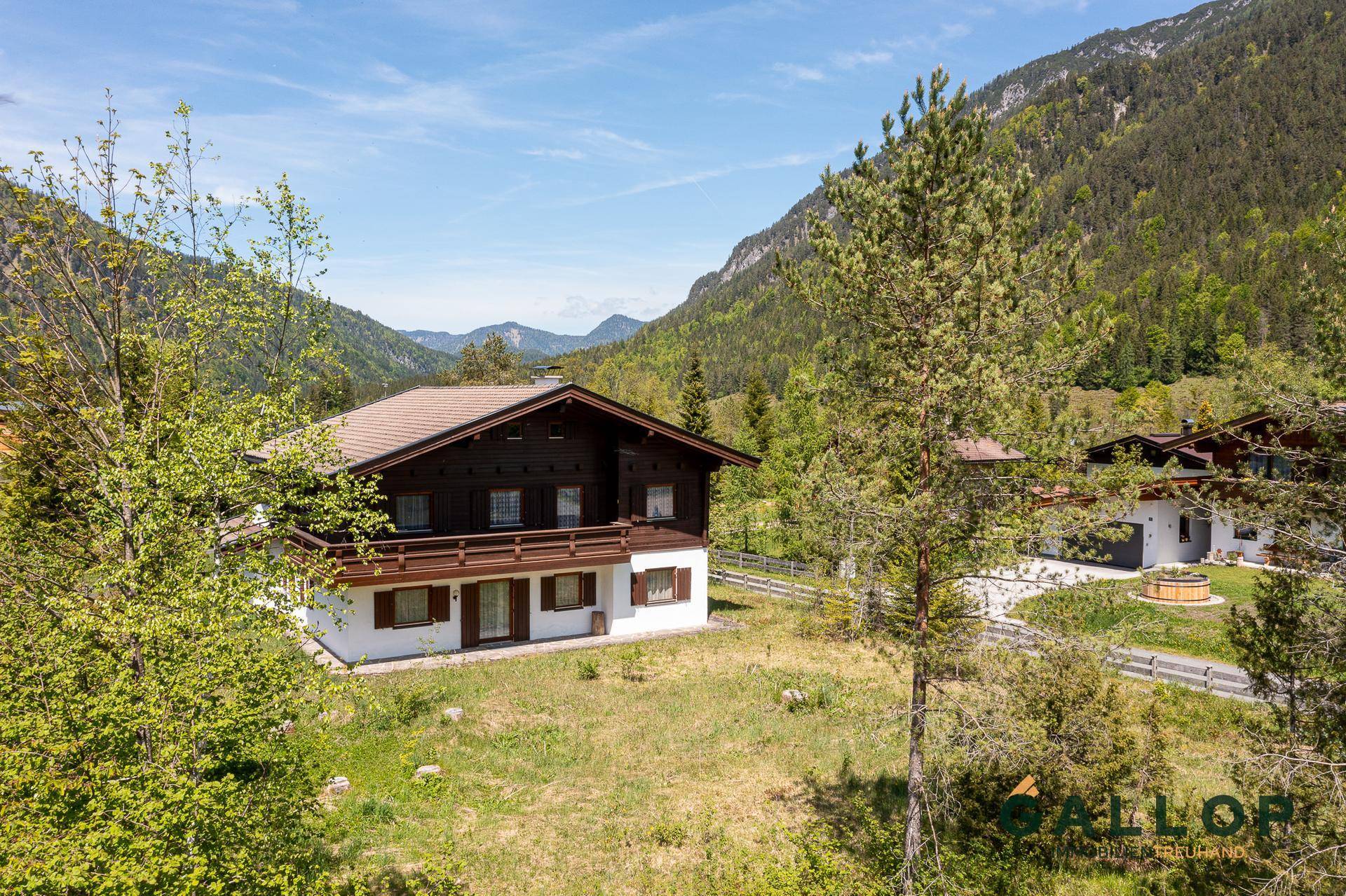 Panoramablick auf das Haus im alpinen Stil inmitten einer grünen Berglandschaft.