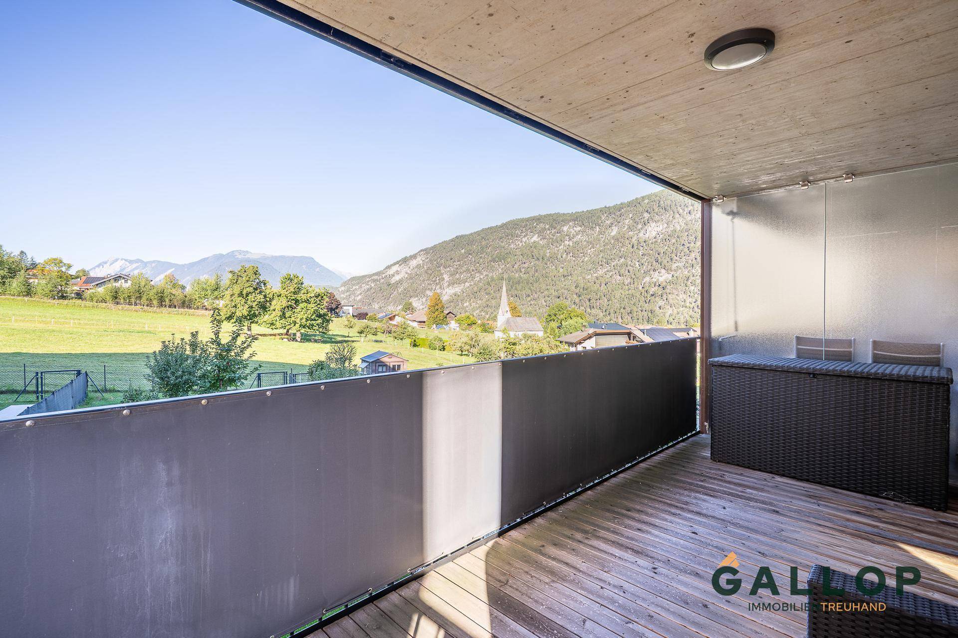 Geräumiger Balkon mit Holzboden und weitem Blick auf die umliegende Berglandschaft.