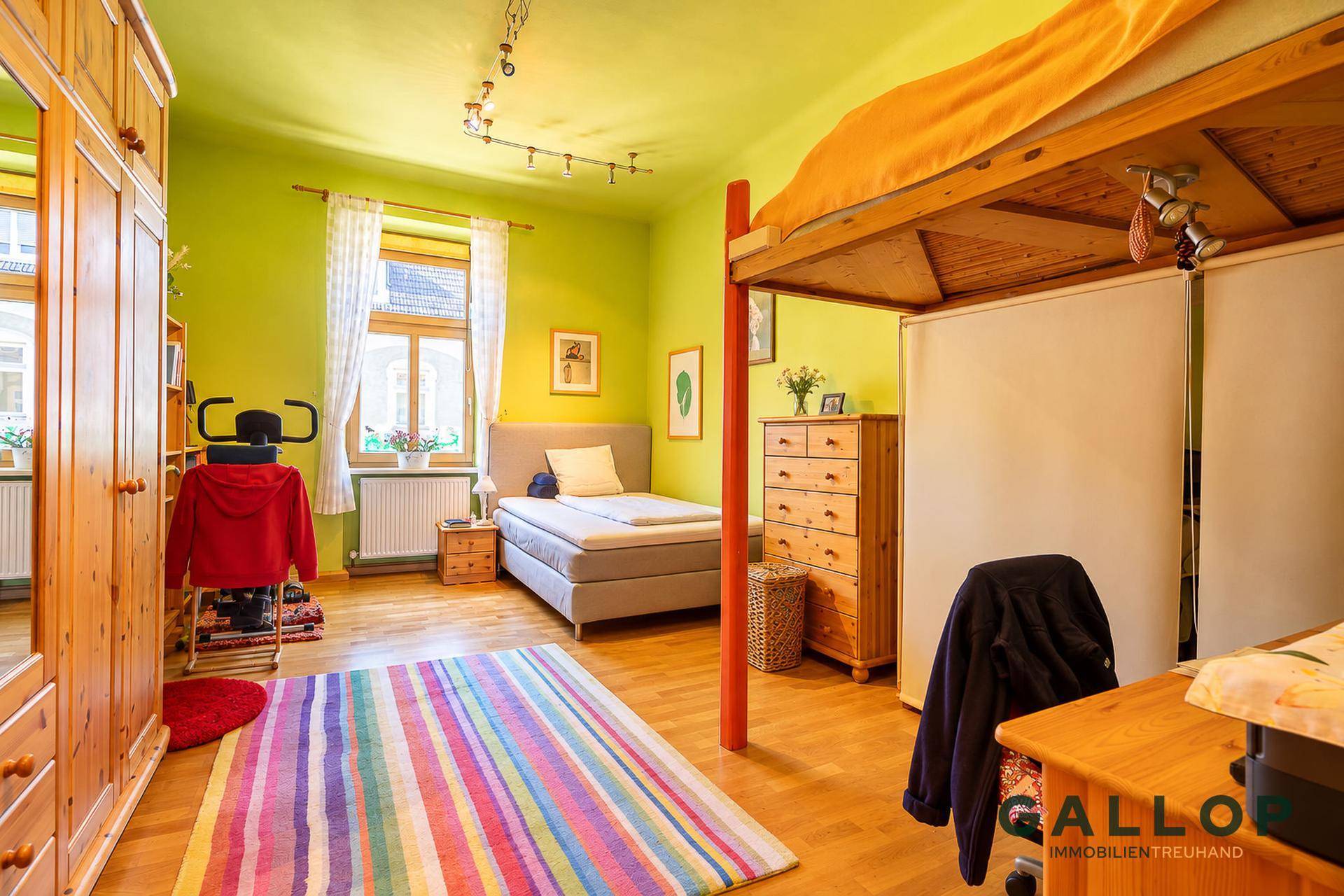 Helles Schlafzimmer mit Holzboden, Kleiderschrank und einem Hochbett, ideal für Kinder oder Gäste.