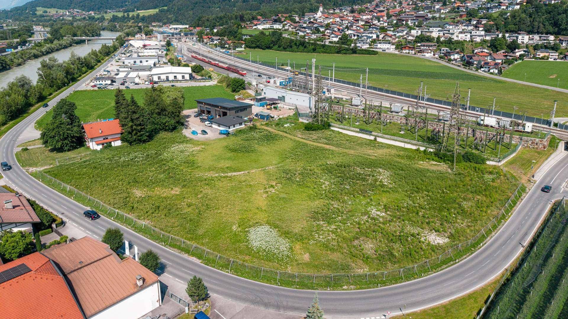 Luftaufnahme eines großen grünen Grundstücks, umgeben von Straßen, Häusern und Bahngleisen.