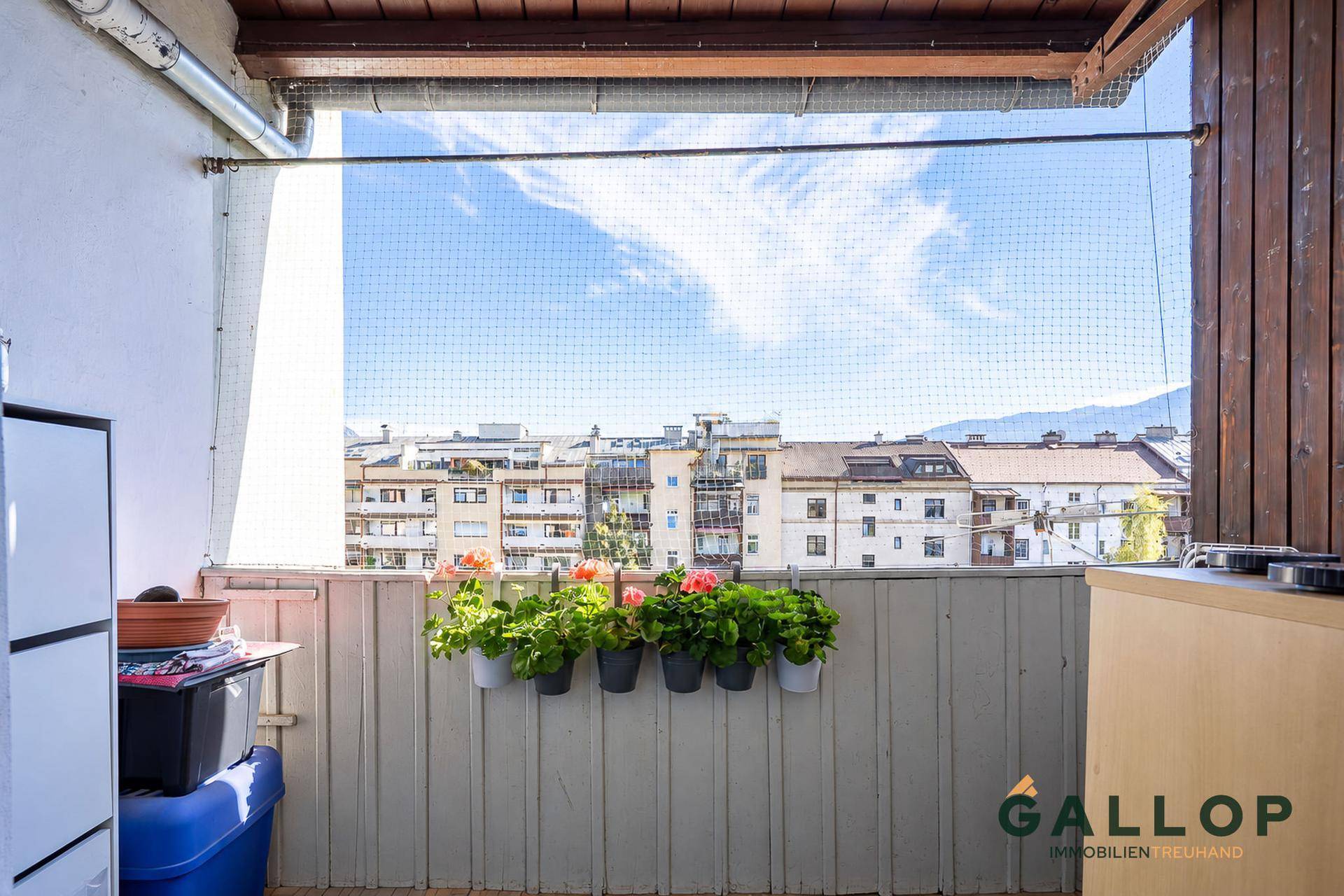 Kleiner Balkon mit Blumenkästen und Blick über die Dächer der Stadt.
