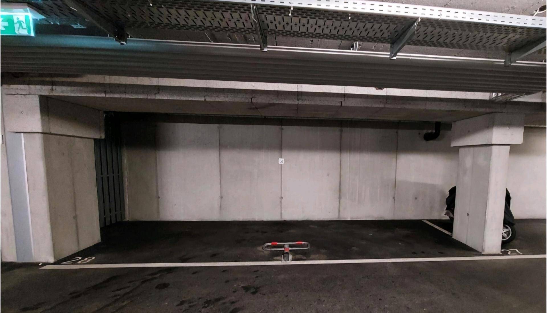 Geräumiger Tiefgaragenstellplatz mit Betonstützen und Deckeninstallationen in einem gepflegten Zustand.