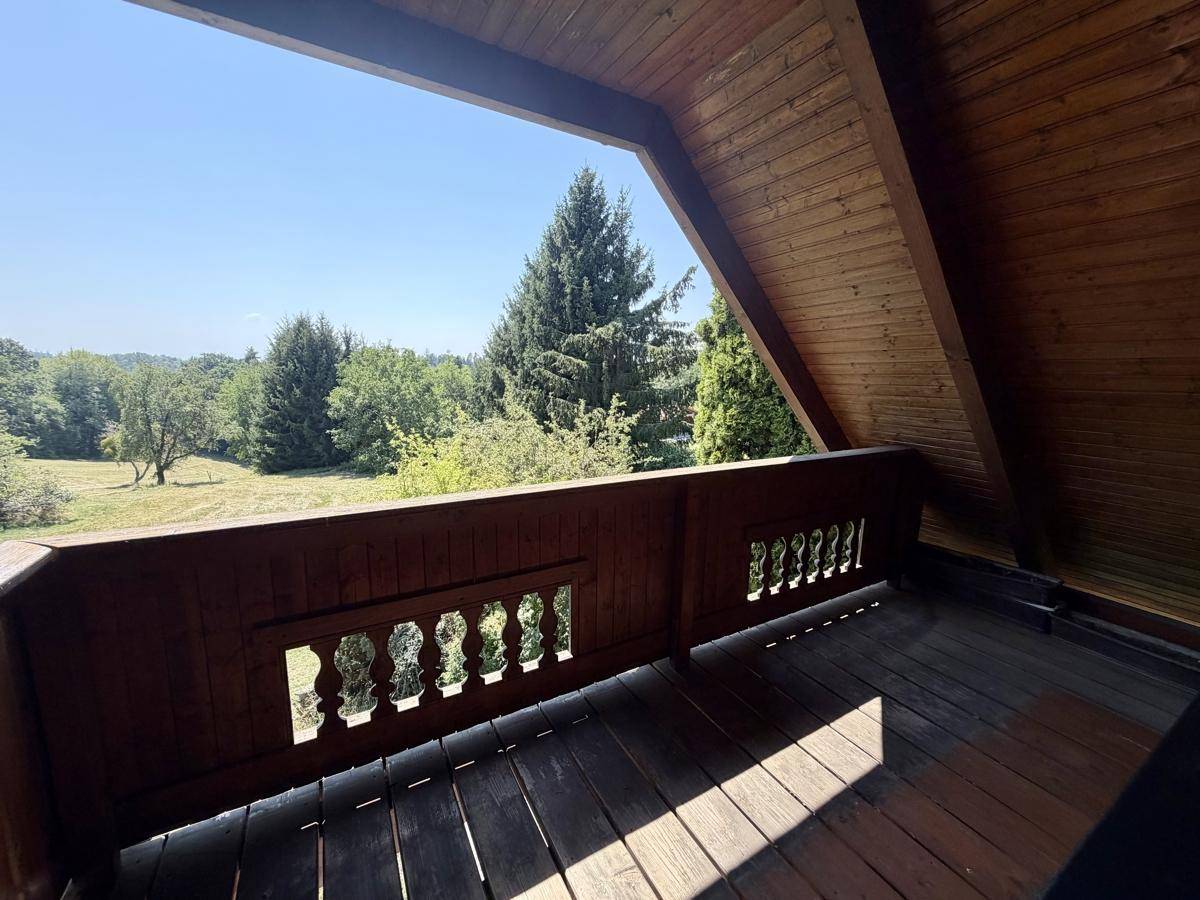 Rustikaler Holzbalkon mit schöner Aussicht ins Grüne, ideal zum Entspannen im Freien.