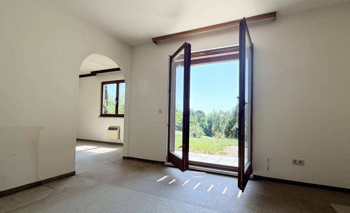 Geräumiges Wohnzimmer mit Zugang zum Garten und Blick ins Grüne, bereit zur individuellen Gestaltung.