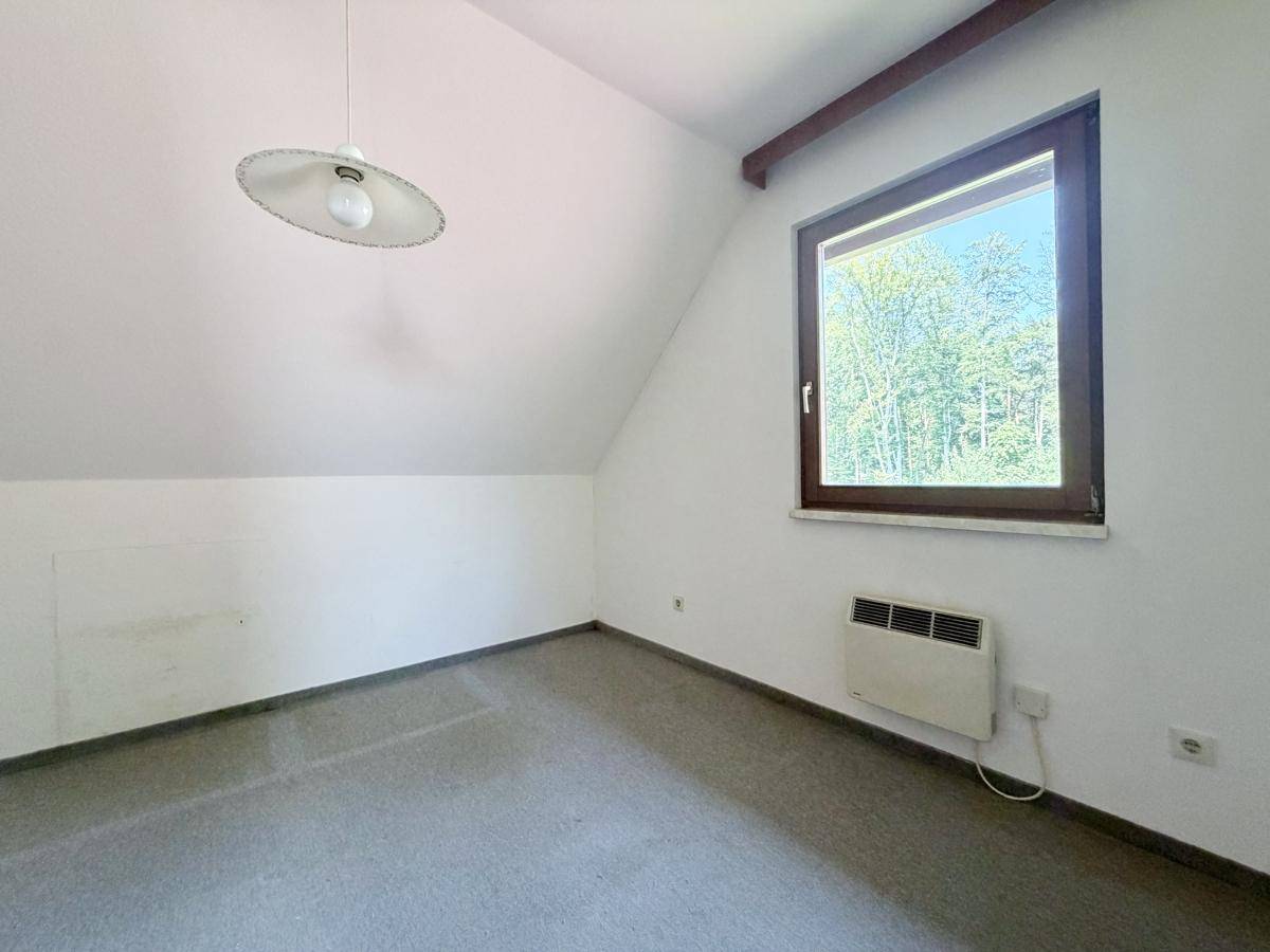 Dachzimmer mit schräger Decke und Fenster, bietet einen ruhigen Rückzugsort.