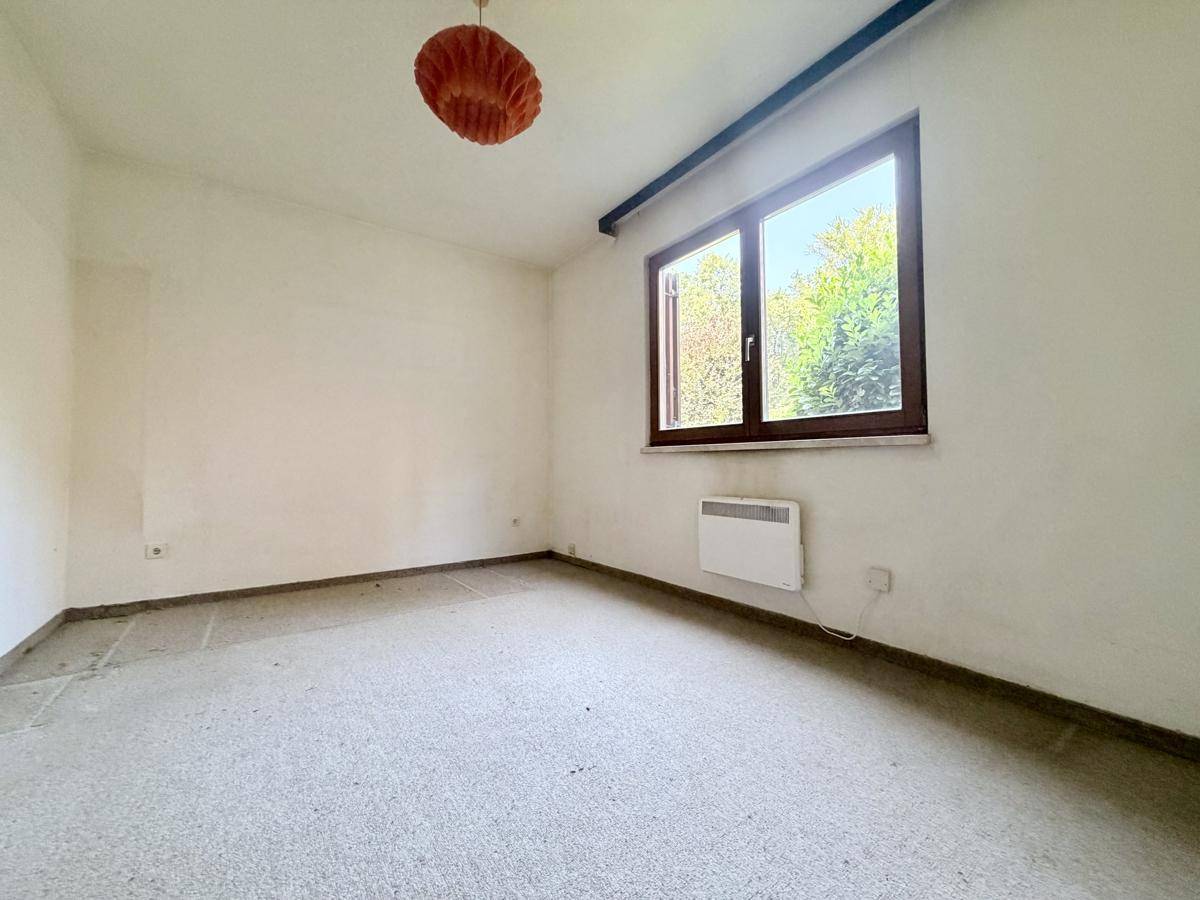 Schlafzimmer mit großem Fenster und Blick ins Grüne, bietet viel natürliches Licht.