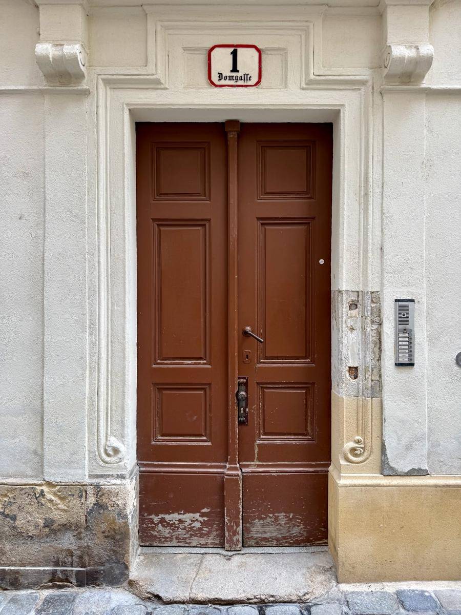 Traditionelle braune Holztür mit Hausnummer und historischem Türrahmen in einer Altstadtgasse.