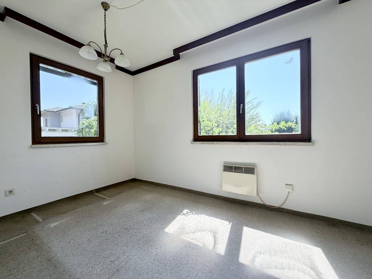 Helles Zimmer mit zwei Fenstern und Blick nach draußen, ideal für Wohn- oder Schlafbereich.