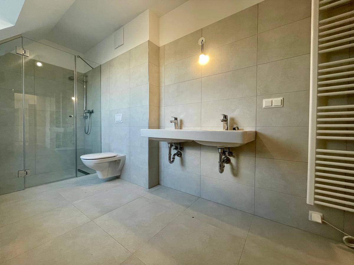 Modernes Badezimmer mit Doppelwaschbecken, bodengleicher Dusche und beheiztem Handtuchhalter.