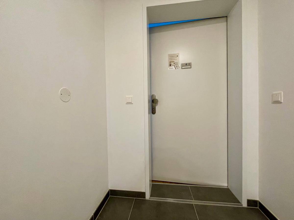 Eingangsbereich mit dunklem Fliesenboden und weißer Tür, der in die Wohnung führt.