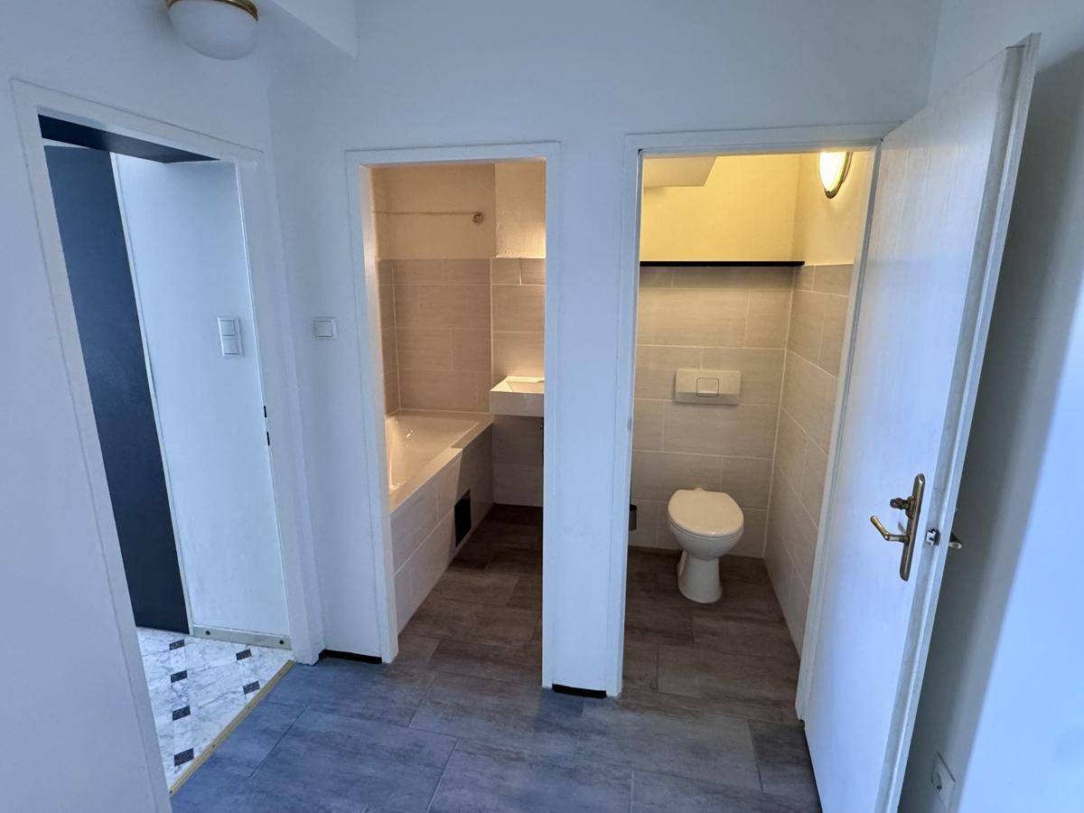 Zwei separate Räume: ein Badezimmer mit Badewanne und ein separates WC mit modernen Fliesen.