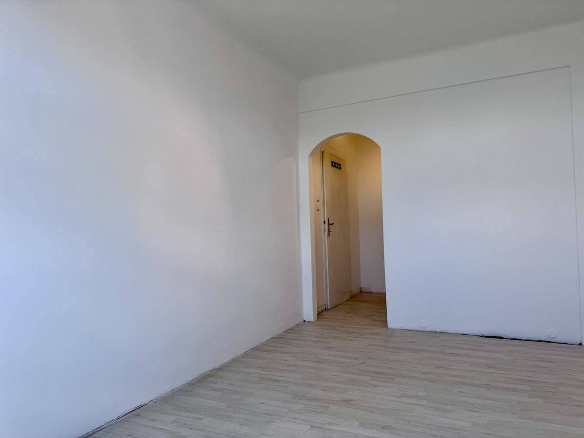 Heller Raum mit Laminatboden und einem eleganten Bogen, der zum Flur führt.