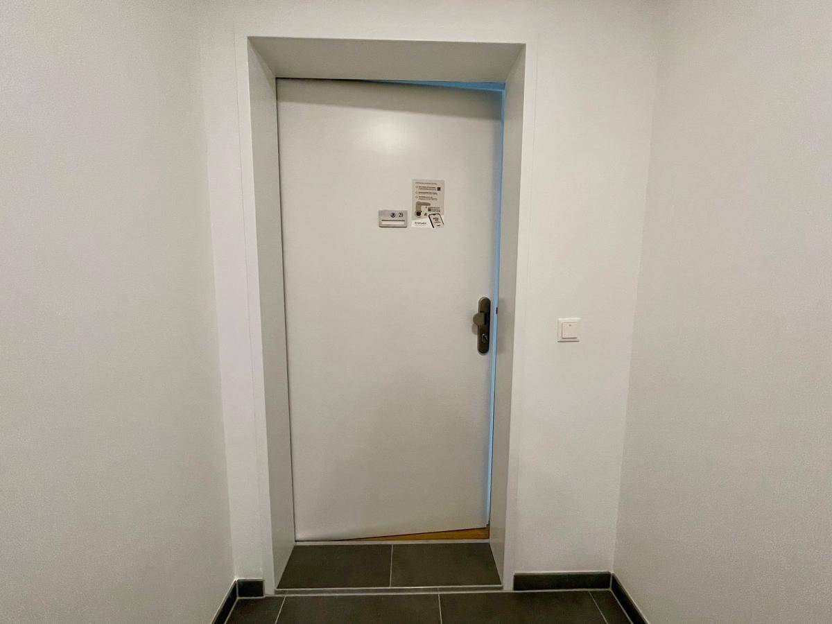 Eingangsbereich mit Fliesenboden und einer schlichten weißen Tür, die zum Wohnbereich führt.