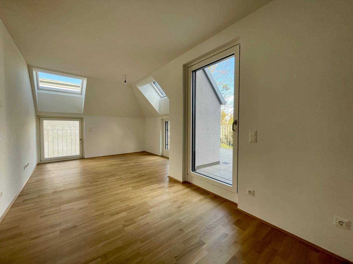 Geräumiger Wohnbereich mit Holzboden, Dachfenstern und direktem Zugang zum Außenbereich.